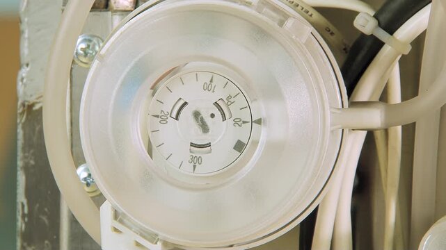 An intricate dial meticulously displays current status, surrounded by neat wiring and cable ties, inside an essential network panel, quietly working to maintain seamless data flow in daylight.