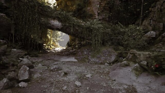 Sunlit mossy cave entrance revealing forest, limestone arch framing distant canopy, dappled light filtering through leaves, rocky floor with scattered boulders