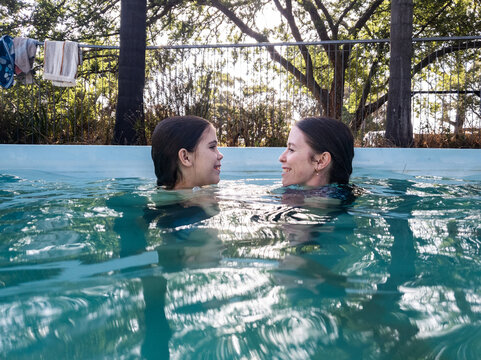 Sisters swimming together in backyard pool in Australia