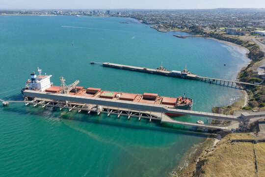 Aerial view of a cargo ship at a coastal wharf over a blue sea