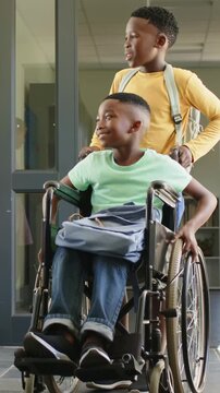 Teen boy pushing wheelchair school hall, approaching peer causing child high-fiving, icon appearing