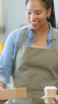 Cafe server greeting customer after order request, placing cardboard box and two cups on table