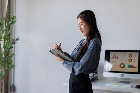 Asian businesswoman writing daily plan in modern office