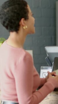 Mid-adult woman showing phone at retail counter, tapping to pay while animated check appearing