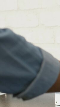Vertical video: Left arm entering with rolled sleeve, pale watch reaching knob adjusting in kitchen