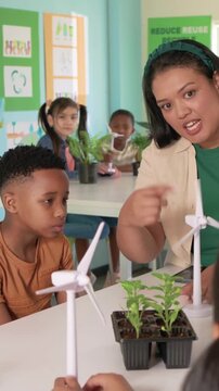 Vertical video: Entering teacher in green top spinning turbine teaching plants and energy at school