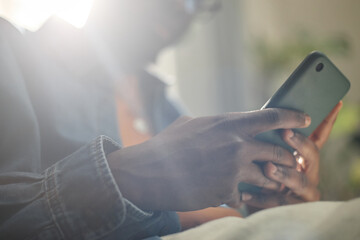 Fototapeta premium Close up of Black young adult man using smartphone for mobile messaging and online browsing. Suitable for social media, fintech, app promotion, digital communication campaigns