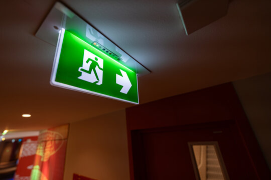 An emergency fire exit light box with arrow hangs from a hospital ceiling, combining evacuation drill concept with clear safety direction and escape guidance.