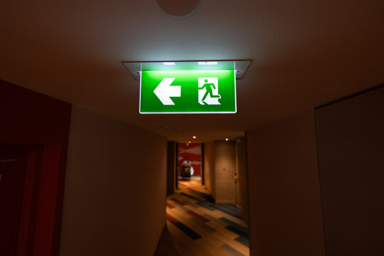 Green emergency exit signs glow above indoor corridors, combining clear direction guidance with fire safety planning and evacuation readiness.