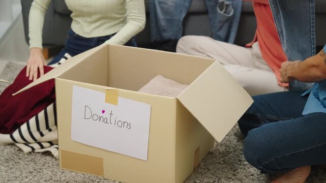 close up group of asian young adults sorting and packing clothes into donation box. community support, and charitable giving