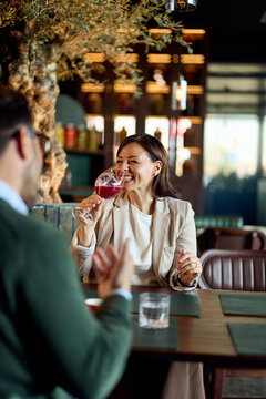 Business Colleagues Laughing Over Wine During Casual Restaurant Meeting and Networking Conversation
