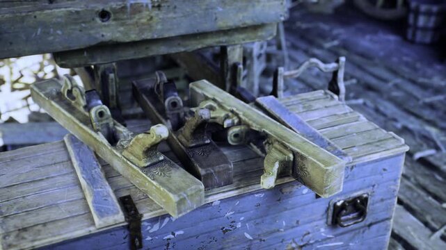 Detailed view of old bench vise and wooden jigs on roughhewn bench, clamps and guides arranged for precise cuts, cool natural light accentuates worn edges