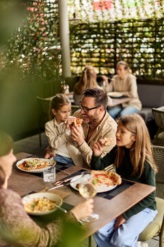 Happy Family Eating Pizza Together At Outdoor Restaurant Patio During Casual Weekend Lunch