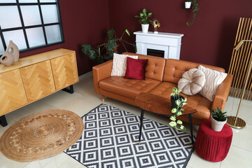 Naklejka premium Interior of modern living room with cozy brown sofa, coffee table, ottoman and fireplace