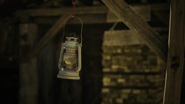 Worn lantern illuminating prospector cabin interior, casting amber light on wooden rafters and dust motes, tin cups and tools blurred in background, nostalgic
