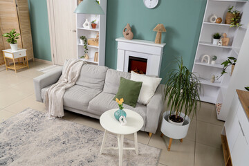 Naklejka premium Interior of stylish living room with grey sofa, shelf units and plants