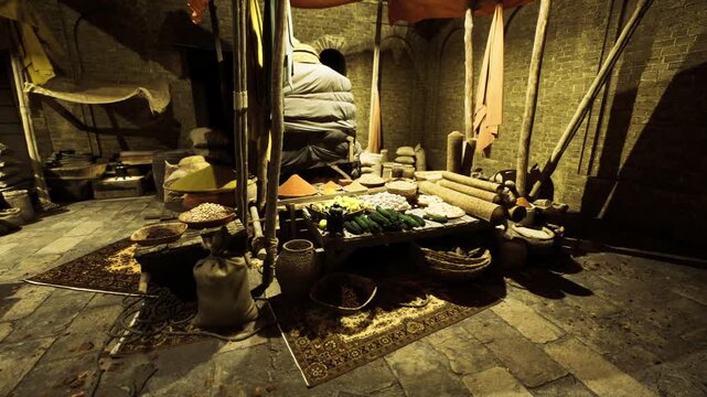 Vendor arranging sacks and baskets behind low table, hands unseen but motion implied, piles of spices grains and vegetables stacked on woven trays, dim market