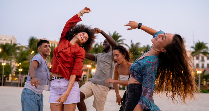 Energetic friends celebrating a summer party on the beach at sunset, embodying the carefree vacation