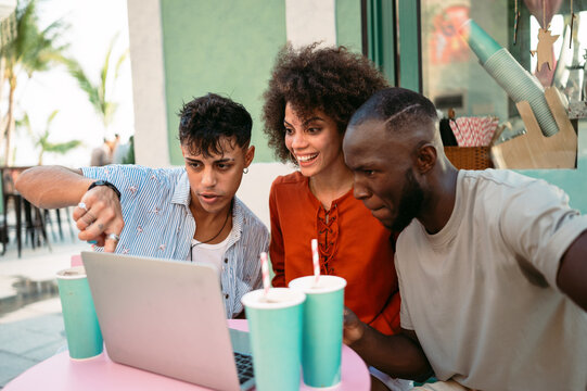 Students gather for a friendly cafe study session, learning together with a laptop, discussing ideas