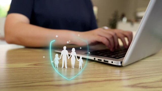 Digital family insurance and life protection concept with person using laptop and glowing security shield icon on wooden table