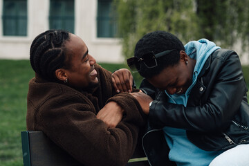 Happy black friends sharing moment of laughter in park, enjoying connection and friendship outdoors