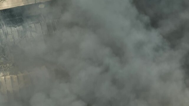 High-angle drone shot of dense smoke clouds from a factory fire, creating heavy haze and poor air quality, reflecting today&rsquo;s industrial emissions challenges and global environmental impact. 4k.
