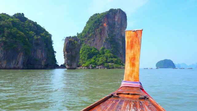 Long-tail boat cruising through a tropical bay with limestone cliffs, promoting eco tourism, sustainability, low-impact travel, and conservation of marine ecosystems in a changing climate. Thailand.