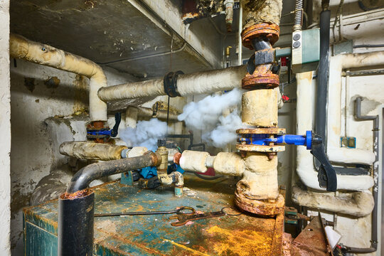 Old boiler room pipes leaking steam