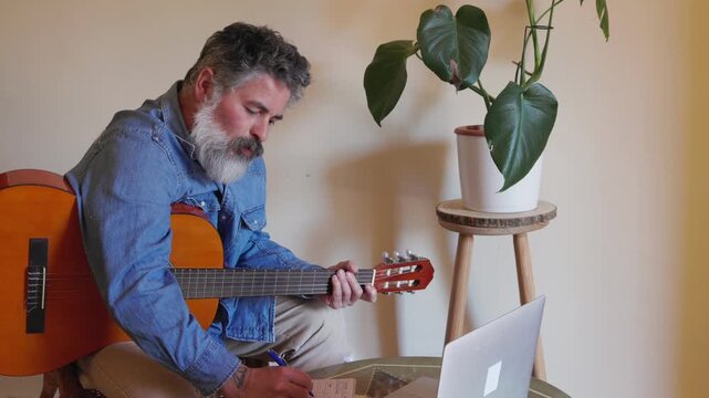 Mature man learning guitar through online course at home
