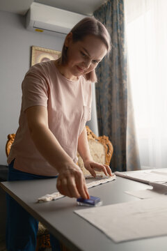 Woman crafting and measuring fabric at home table, focused on sewing and DIY project