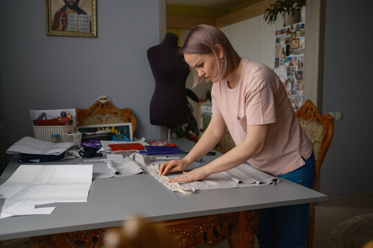 Woman seamstress working on fabric pattern in home sewing workshop preparing garment trim