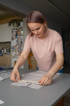 Woman sewing fabric by hand at home preparing a craft project on a kitchen table