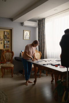 Woman sewing garment pattern in a home studio tailor workshop, focused on dressmaking and design