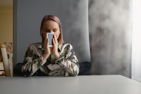 Young woman holding tarot cards to her face during a quiet home tarot reading at a table