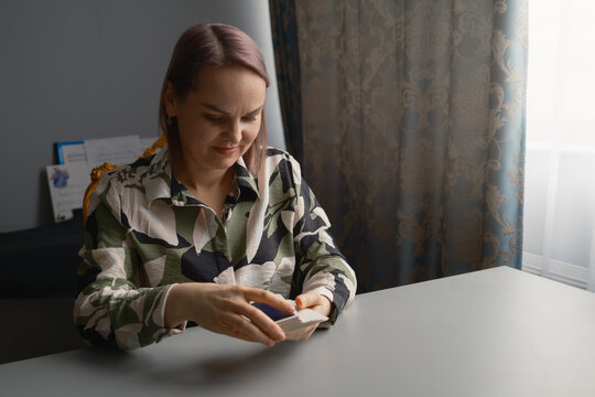 Woman shuffling tarot cards at a table during a private tarot reading session in a cozy room