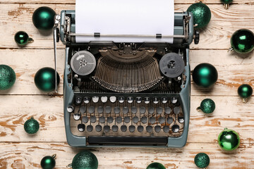 Fototapeta premium Vintage typewriter with green Christmas balls on white wooden background