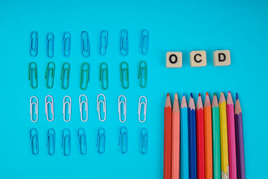 Top View Of OCD Tiles With Neatly Arranged Paper Clips And Colored Pencils For Mental Health Concept