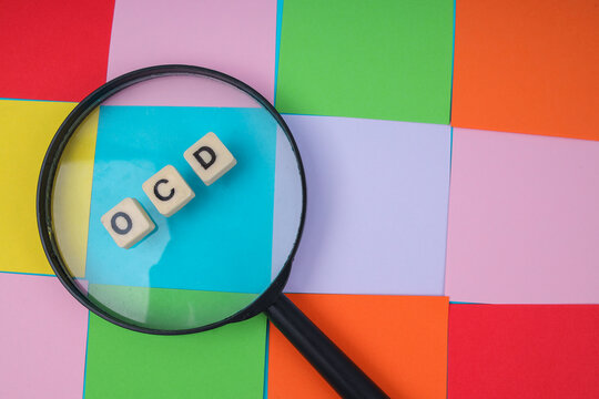 Close Up Of Magnifying Glass Over Skewed OCD Tiles On Colorful Grid Concept