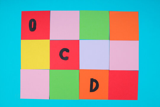 Top View Of Black OCD Letters On Colorful Square Paper Grid For Mental Health Concept