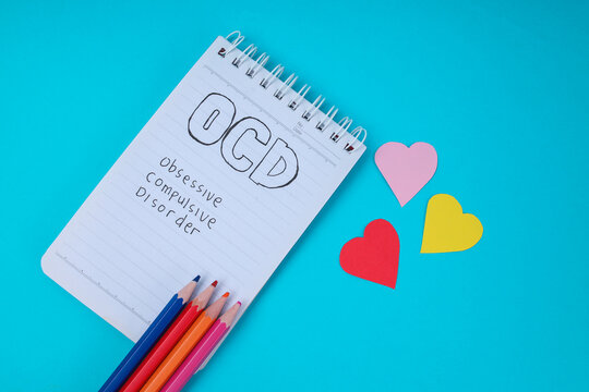 Top View Of Notepad With OCD Handwritten Text Colored Pencils And Hearts For Mental Health Concept