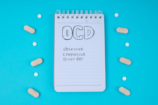 Top View Of Notepad With OCD Text Surrounded By Symmetrically Arranged Pills For Mental Health Concept