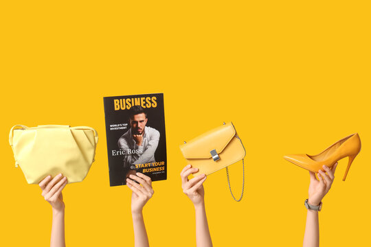 Female hands with magazine, high heel and stylish bags on yellow background