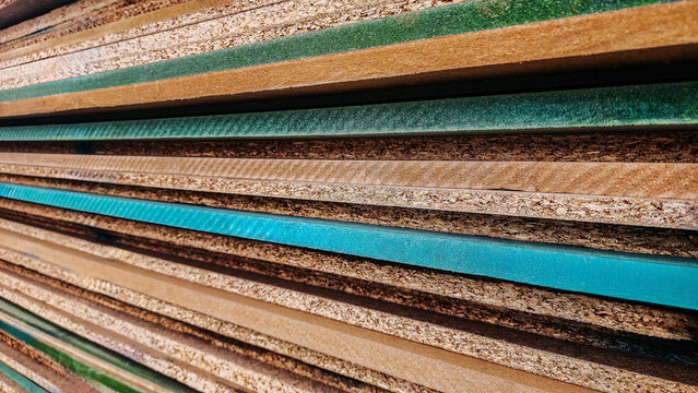 Stacked plywood and particle board panels with layered edges, industrial wood texture background for construction, carpentry, furniture production and manufacturing concepts.