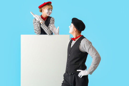 Couple of pantomimists with blank poster on blue background