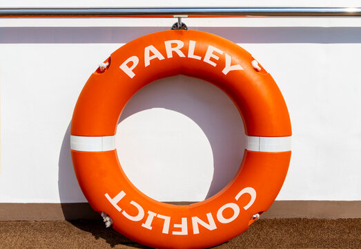 Parley instead conflict symbol. Concept words Parley and Conflict on beautiful orange lifebuoy. Beautiful white ship board background. Social and parley instead conflict concept. Copy space.