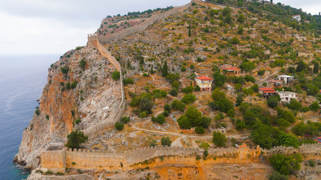 Alanya, Turkey. Aerial drone flight along medieval fortress wall on seaside cliff with rocky coastline extending into Mediterranean Sea.. Aerial View