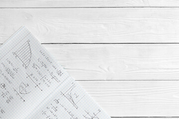 Fototapeta premium Copybook with handwritten maths formulas on white wooden background