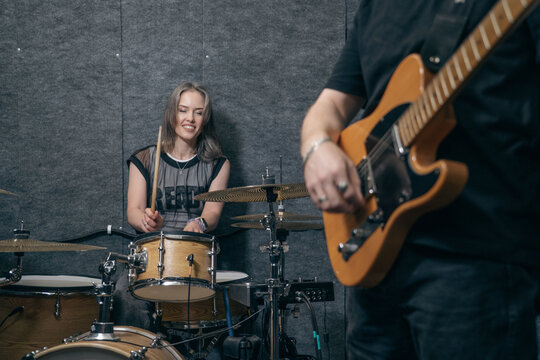 Band rehearsal female drummer with guitarist in foreground. Music collaboration, live practice, indie performance and creative studio session.
