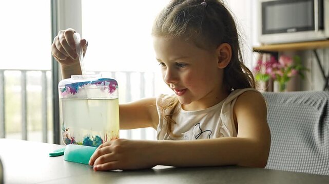 Little girl using pipette to add air bubbles into aquarium with artemia. Learning through hands on activity and early science education concept.