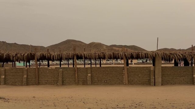 Series Of Rustic Strawroofed Cottages Arranged Along Mountain Landscape In Distance